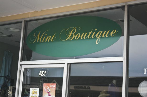 Mint Boutique Arlington Heights.  Green oval backing with cursive gold lettering. 